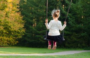 Young girl on a swing with trees in front of her